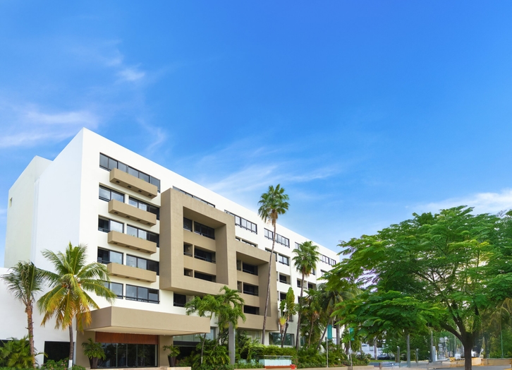 Facade of Smart Cancun hotel with its balconies and palm trees in front